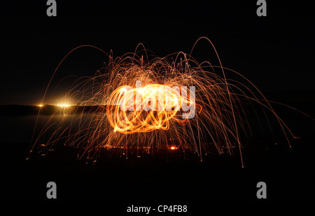 lite steel wool spun creating amazing lines of light and contrast with the night sky Stock Photo