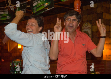 Two 50/60 somethings party and dancing in a bar late into the night while on holiday - forever young. Stock Photo