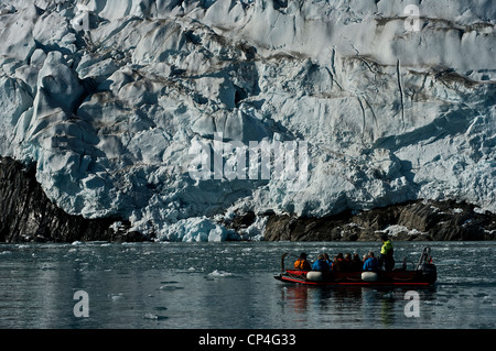 Greenland - West Coast - Tourists in an excursion by rubber boat watching the rocks, covered by ice. Stock Photo