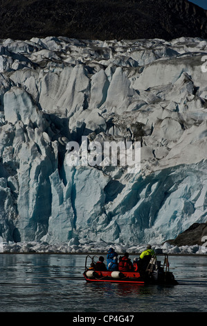 Greenland - West Coast. Tourists in excursion on a rubber boat watching rocks covered by ice. Stock Photo