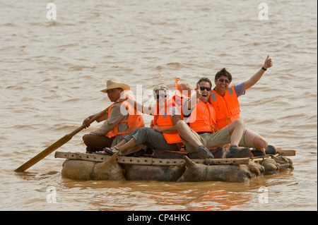 Happy European tourists float on the Yellow River on traditional sheepskin rafts - one of the 'rides' at the Shapatou Theme Park Stock Photo