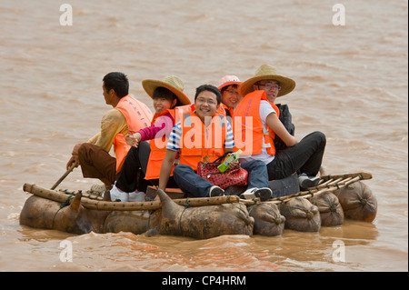 Happy Chinese tourists float on the Yellow River on traditional sheepskin rafts - one of the 'rides' at the Shapatou Theme Park. Stock Photo