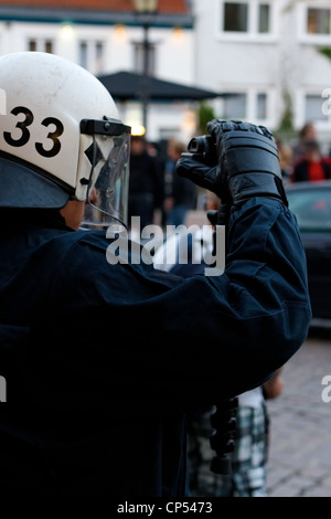 Police officer in full riot gear films violent protesters during a May Day demonstration in Hamburg, Germany on May 1, 2012. Stock Photo