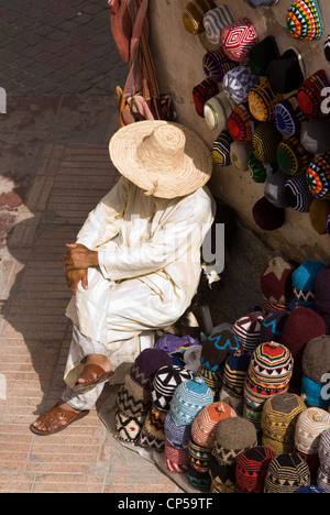 a seller chills out outside his shop trading with artisanal products for sale to tourists, Essaouira, Morocco Stock Photo