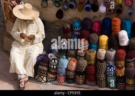 a seller chills out outside his shop trading with artisanal products for sale to tourists, Essaouira, Morocco Stock Photo