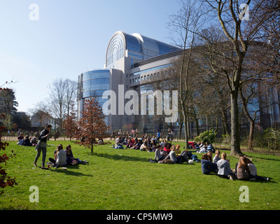 Young people sitting on the grass behind the European Parliament buildings at lunchtime, Brussels, Belgium Stock Photo