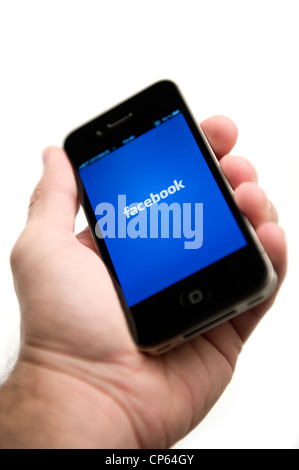 Hand holding iPhone with selective focus on Facebook logo Stock Photo