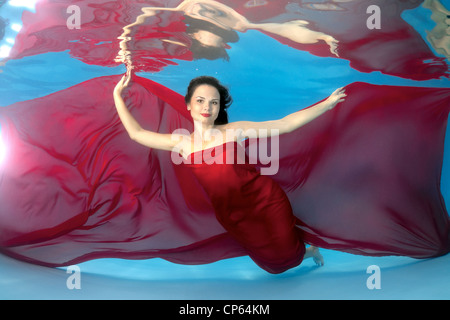 A young woman with big hair posing in a pool underwater Stock Photo