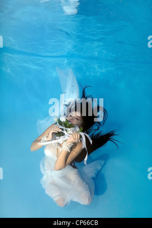 A young woman with big hair posing in a pool underwater Stock Photo