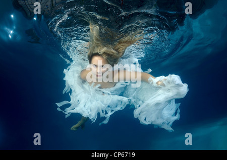 A young woman with big hair posing in a pool underwater Stock Photo