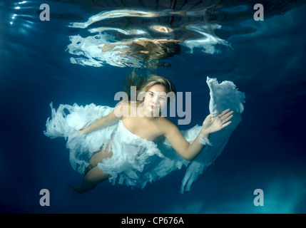 A young woman with big hair posing in a pool underwater Stock Photo