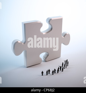 Tiny people looking at a jigsaw puzzle piece Stock Photo