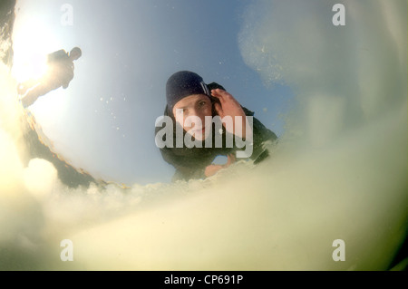 Diver looking into an ice hole, subglacial diving, ice diving, in the frozen Black Sea, a rare phenomenon, last time it occured Stock Photo