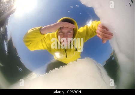 Diver looking into an ice hole, subglacial diving, ice diving, in the frozen Black Sea, a rare phenomenon, last time it occured Stock Photo