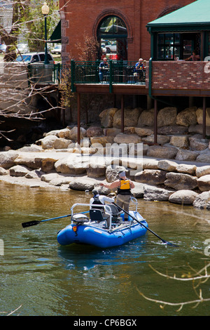 Patrons at Boathouse Cantina restaurant watch from outdoor deck as fly fishermen in a guided boat floats the Arkansas River Stock Photo