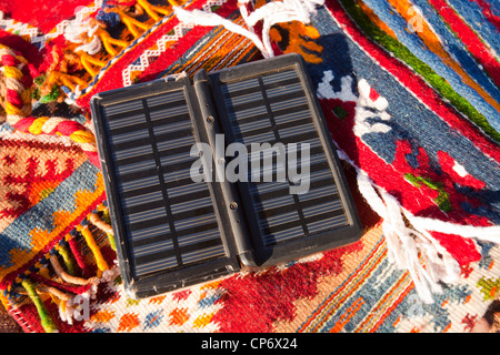 Berber Moroccan woven cloth rugs and bags in the Anti Atlas mountains of Morocco, North Africa, with a solar charger. Stock Photo