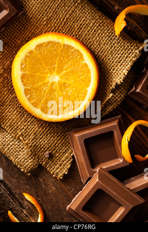 Orange Slice with Chocolate Squares on Jute and Wood Stock Photo