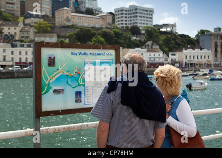 UK, England, Devon, Torquay Harbour, middle aged couple looking at Bay Walks Measured Mile sign Stock Photo