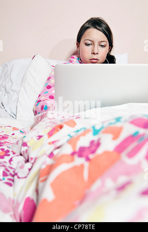 Preteen Girl on Laptop in Bed Stock Photo