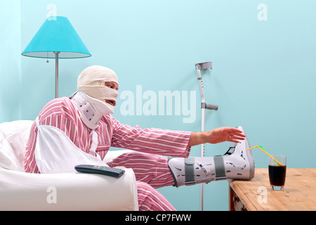 Photo of a injured man in pyjamas with a bandaged head, leg cast, arm sling and neck brace Stock Photo