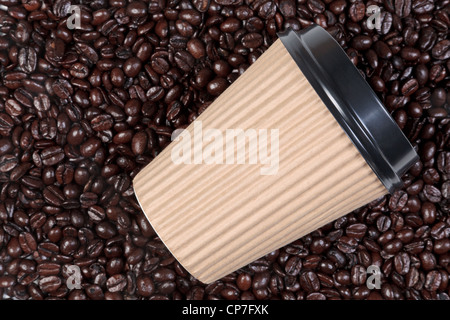 Photo of a takeaway disposable paper coffee cup on a background of fresh roasted arabica and robusta beans. Stock Photo