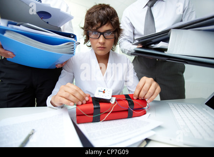 Serious secretary with dynamite being surrounded by big heaps of papers Stock Photo