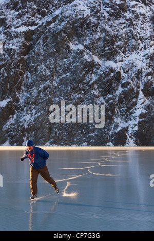 Man ice skating in front of Saddlebag Glacier, Chugach Mountains near Cordova, Southcentral Alaska, Winter Stock Photo