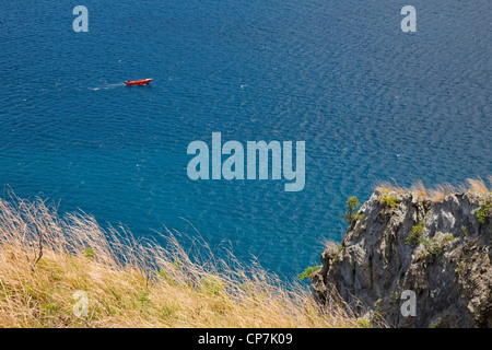 A small red fishing boat with outboard motor off the coast of Dominica near Scott's Head in the south of the island Stock Photo