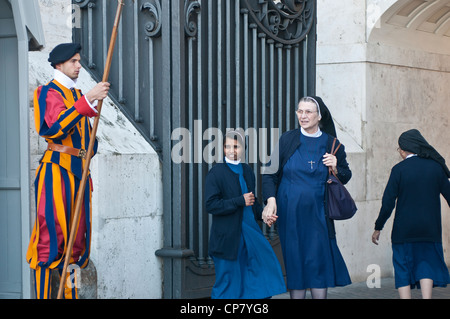 Swiss guard and nuns entering the gate of the Vatican Stock Photo