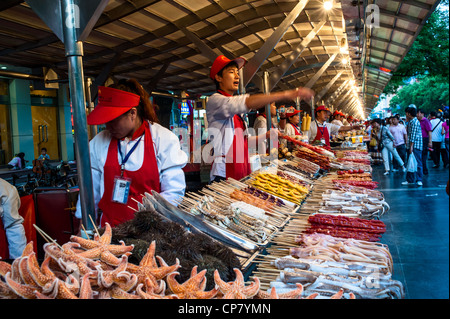 Vendor is eagerly to promote his snacks in Beijing snack night market Stock Photo