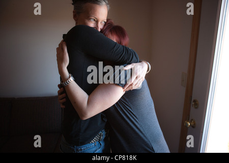 Big sister hugging younger sister at home. Stock Photo