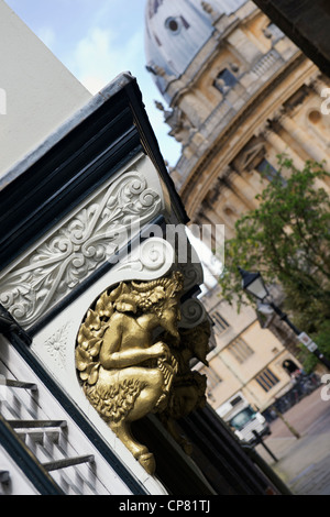 Faun Carvings above the aslan door into Brasenose College in St Mary's Passage  with Radcliffe Camera in the background. Oxford, Oxfordshire, England Stock Photo