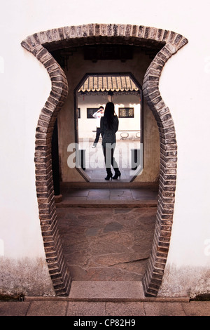 Young asian woman posing for a picture in front of traditional chinese door - Tongli near Shanghai - China Stock Photo