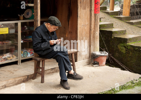 Old man reading sitting on a bench, Huangluo Stock Photo