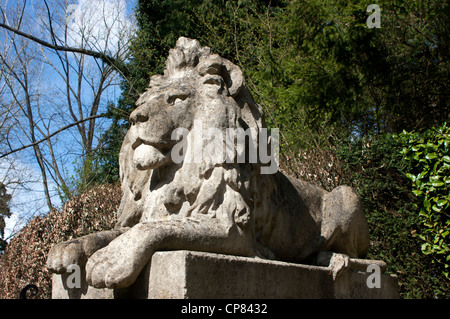 Concrete statue of a lion (one of a pair) seated on gateway pillar at entrance to a mansion in Surrey Stock Photo