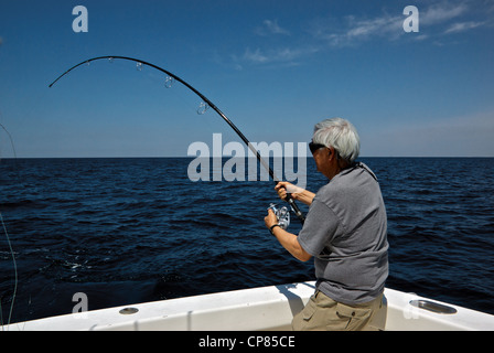 Asian Angler Holding Fishing Rod on a Small Fishing Boat Stock