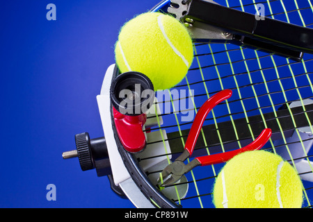 Tennis racket in stringing machine being repaired on blue background Stock Photo
