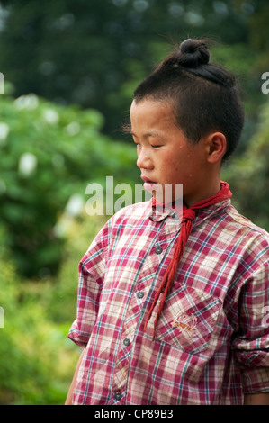Young Basha Miao (Gun Men) boy with traditional hairstyle and red neckerchief, Southern China Stock Photo