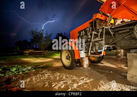 Old tractor standing in the shade during stormy evening.  Poland. 2012 Stock Photo