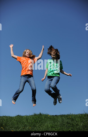 Two young Girls jumping on a sunny day against a blue sky Stock Photo