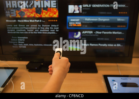 Child making a choice to play Minecraft video game using Apple TV, large screen. Stock Photo