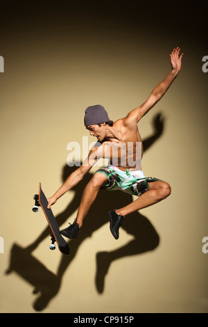 Portrait of Healthy and good looking young caucasian man wearing beanie and umping with skateboard.