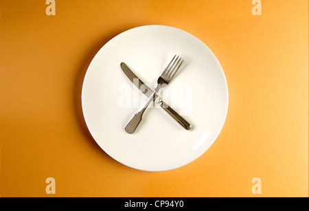 Knife and fork crossed on a clean plate Stock Photo