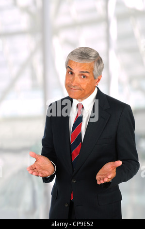Middle aged businessman in modern office setting making a gesture with both hands. Vertical Format. Stock Photo