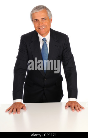 Smiling Middle Aged Businessman leaning on desk with both hands on a white background Stock Photo