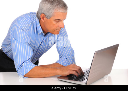 Smiling Middle Aged Businessman leaning on desk using laptop computer isolated on white. Stock Photo