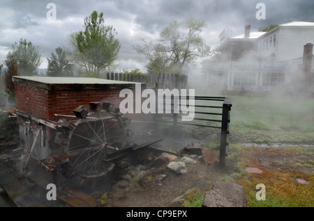 The steam from Hot Lake rises by a waterwheel in front of the Hot Lake Springs Bed & Breakfast in Northeastern Oregon. Stock Photo