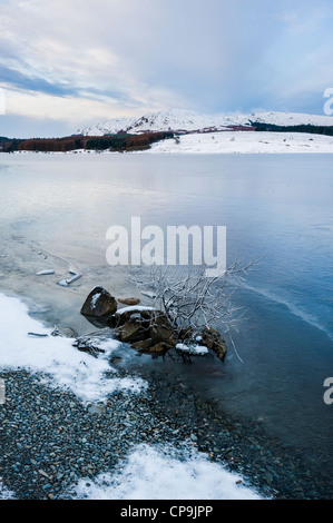 A frozen Clatteringshaws Loch with Craignell in the distance in winter, Galloway Forest Park, Galloway, Scotland, UK Stock Photo