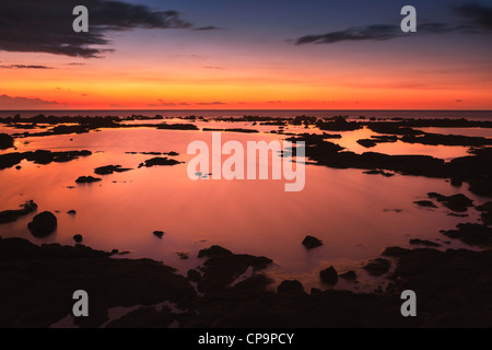 Sunset at the Pacific with lava rocks in the foreground. Stock Photo