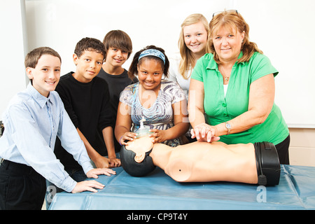 Group of students and their teacher, learning CPR in school. Stock Photo